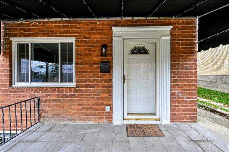 The welcoming entry way covered front porch  features a brand new surface, some newer railings and a decorative awning (2024).