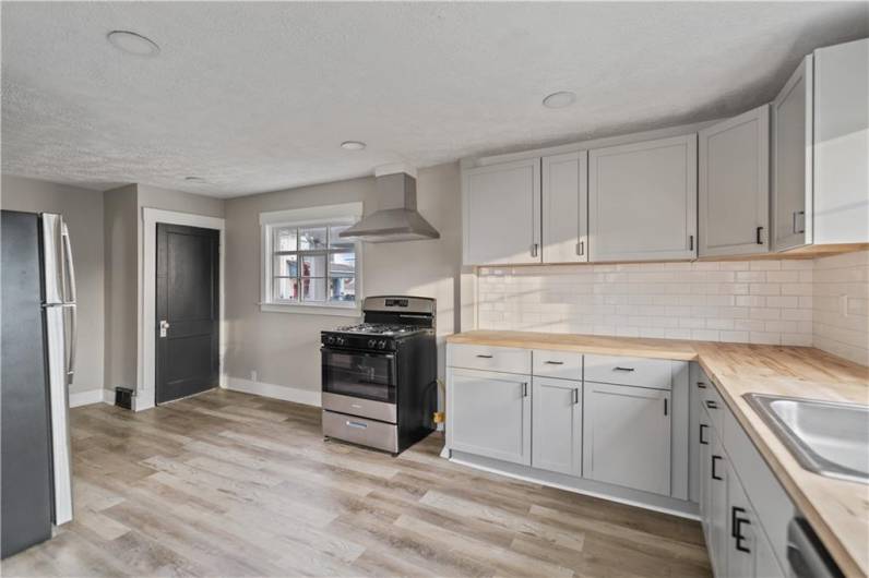 Additional view of the kitchen showcasing the stainless steel hood for the gas range.