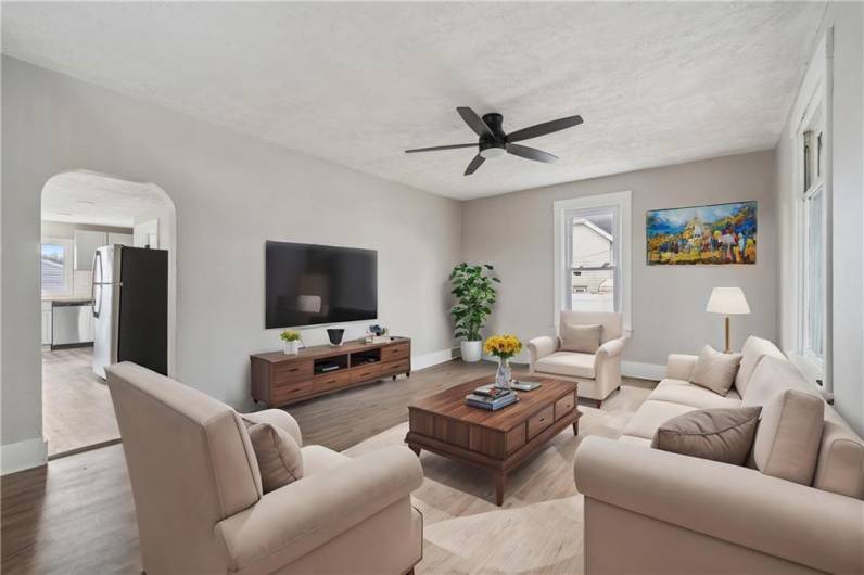 Spacious yet cozy living room is modern yet has warm tones throughout. Wood grain laminate flooring & new ceiling fan for comfort.