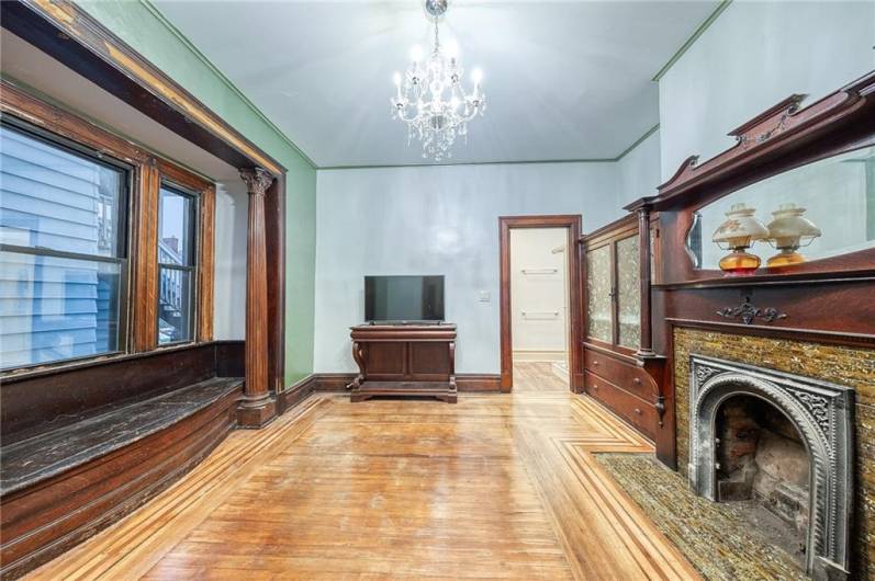 GRAND SIZED DININGROOM WITH DECORATIVE FIREPLACE AND A NEARLY ROOM LENGTH WINDOWSEAT.