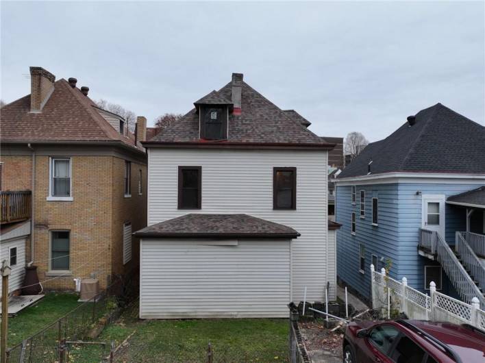 REAR VIEW OF THE HOUSE AND YARD AND OFF STREET PARKING SPACE.