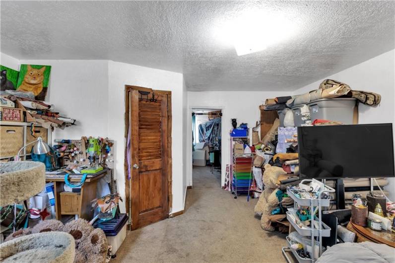 First Floor Unit Living Room with Neutral Carpet. Wood Door Opens to Full Bath.