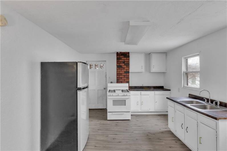 Upper Level Kitchen with White Cabinetry, Laminate Counters, Gas Stove and Refrigerator.