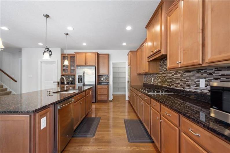 The open concept Kitchen boats Granite Counters, Tile Backsplash, Huge Island, Stainless Steel Appliances, & a Walk-in Pantry.