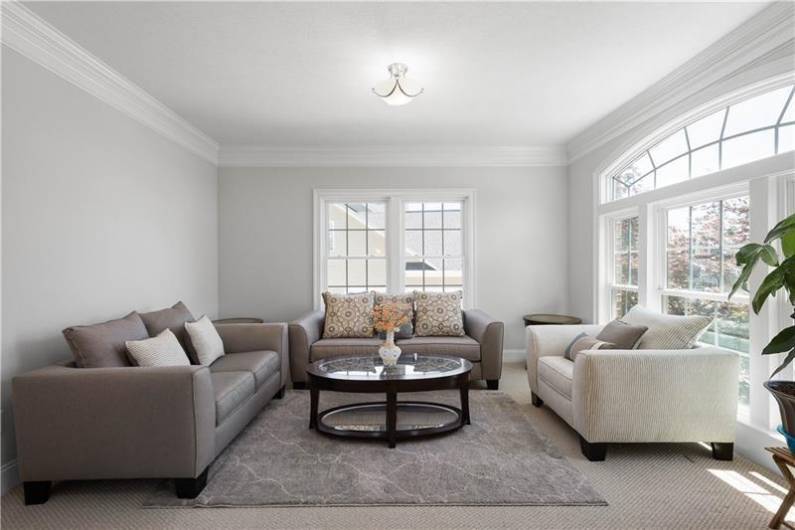 The light and bright Living Room has beautiful moldings and a wall of windows.