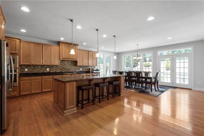 The open concept Kitchen boats Granite Counters, Tile Backsplash, Huge Island, Stainless Steel Appliances, & a Walk-in Pantry.