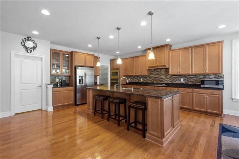 The open concept Kitchen boats Granite Counters, Tile Backsplash, Huge Island, Stainless Steel Appliances, & a Walk-in Pantry.