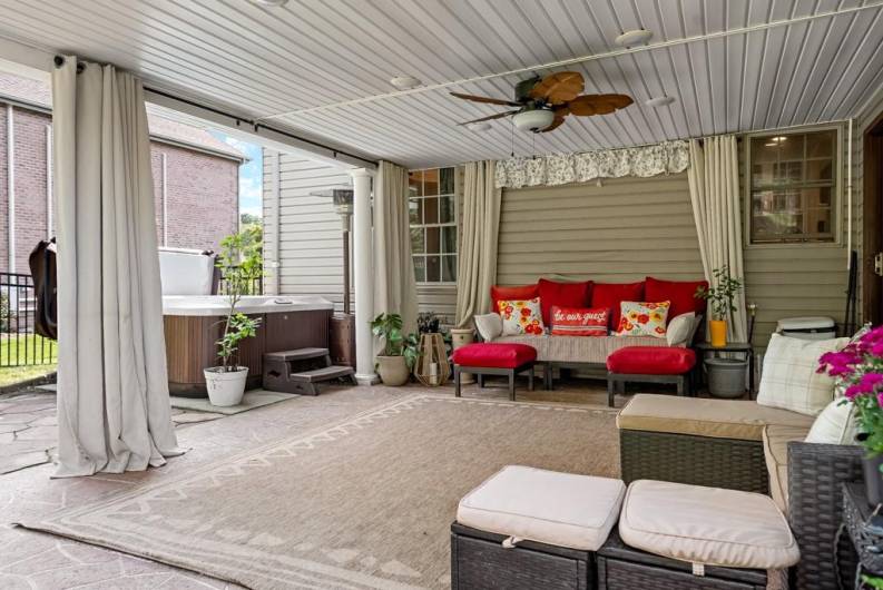 covered patio off of the sunroom with hot tub