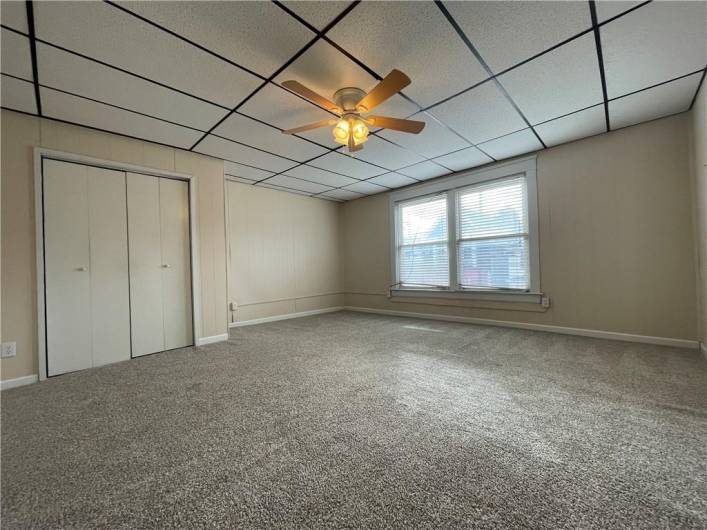 Large primary bedroom has wall to wall carpet, ceiling fan, & large closet.