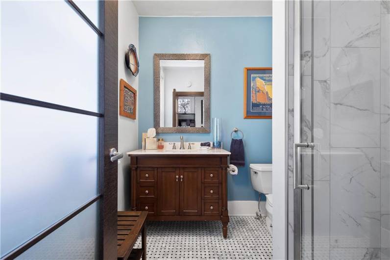 First floor full bath tastefully redone with a new glass door walk in tiled shower and a charming furniture piece vanity.