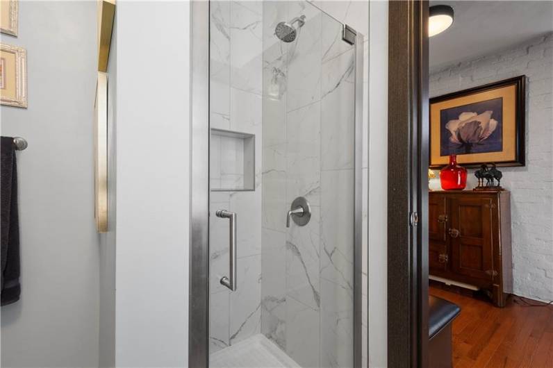 Full tile shower with niche insets and a glass door.