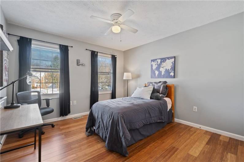 Bright and cheery bedroom has beautiful hardwood floors.