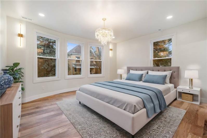 The primary bedroom is an absolute show stopper!!!! Look at that gently curving wall of windows!  Cozy up in your king bed and have sweet dreams in this room!