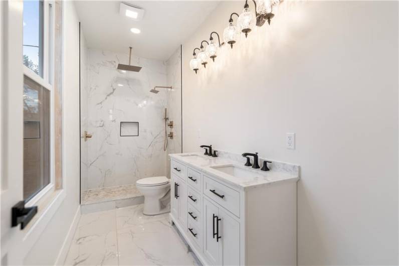 The primary bathroom has large format marble porcelain tiles.  The oversized rain shower head will make it difficult to turn off!  Double bowl sink and plenty of room will make getting ready for work or play a pleasure!