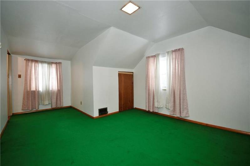 Spacious bedroom with two windows, arched ceiling and storage nook.