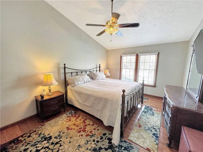 The spacious master bedroom has a dramatic vaulted ceiling and hardwood floors.