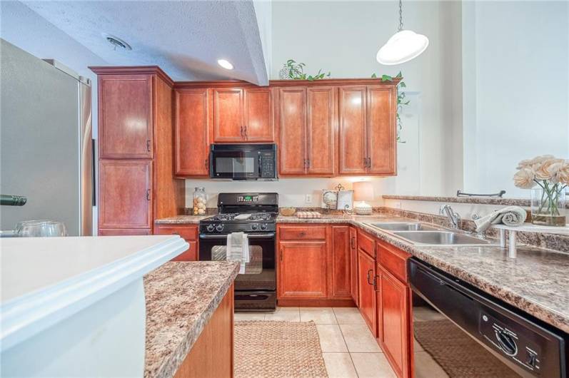 The kitchen boasts solid wood cabinetry, tile flooring, gas range, and high-top seating