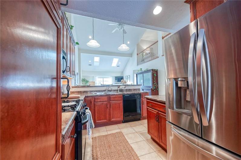 The kitchen boasts solid wood cabinetry, tile flooring, gas range, and high-top seating