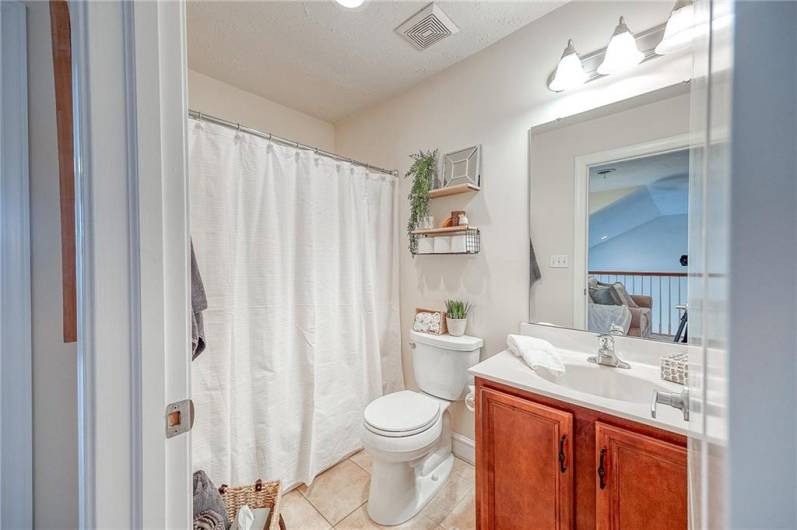 The second floor guest bathroom boasts ceramic tile flooring, solid wood vanity, and a tub-shower combo