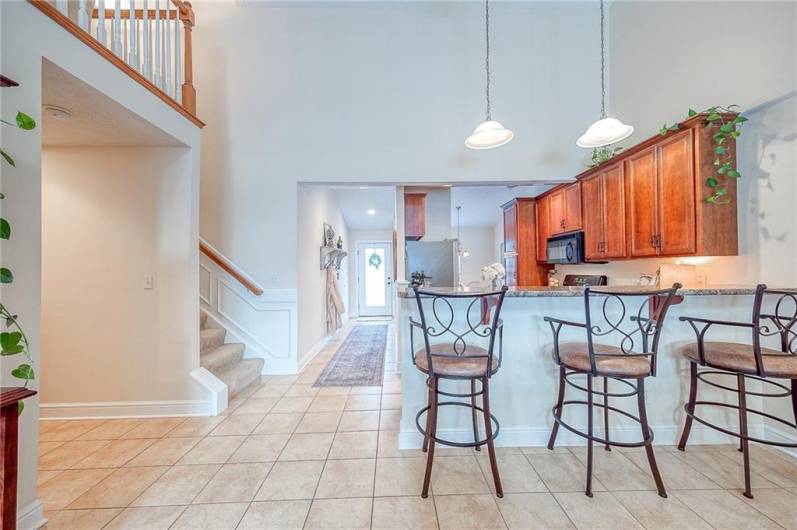 The kitchen boasts solid wood cabinetry, tile flooring, gas range, and high-top seating