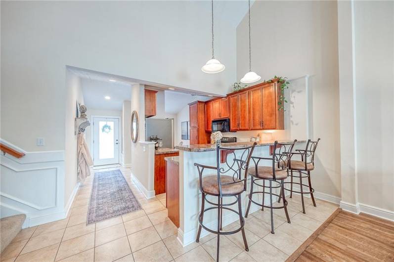 The kitchen boasts solid wood cabinetry, tile flooring, gas range, and high-top seating