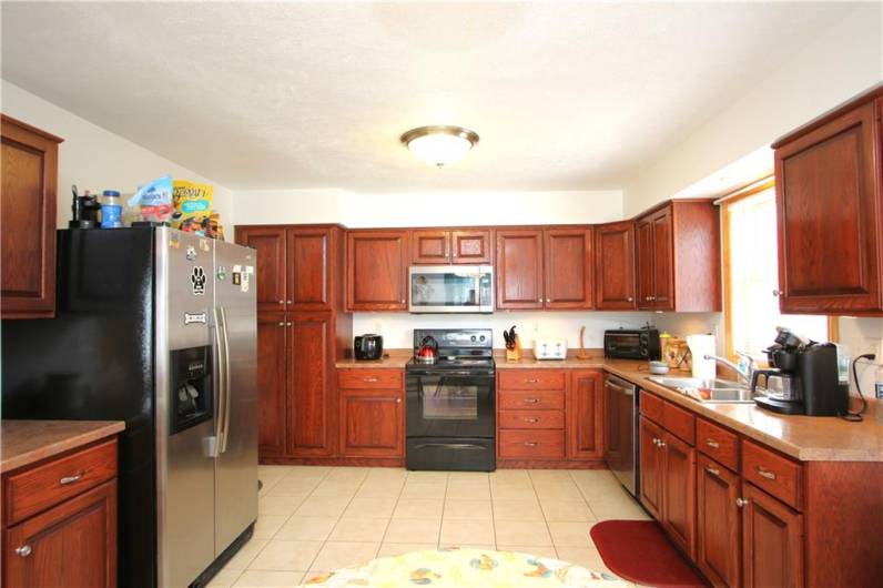 Plenty of Custom Cherry Cabinetry in this Oversized 19x12 Eat-in Kitchen boasting Upgraded Appliances & Ceramic Tile Flooring