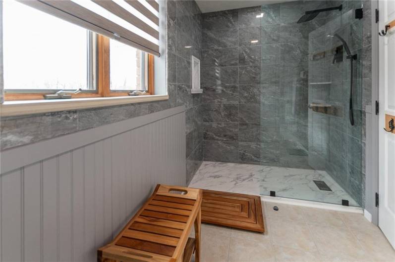 Sapcious shower with glass door, rain shower head and built-in niche.