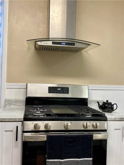 NEW GE 5 burner gas range with integrated griddle.  NEW wall mount range hood