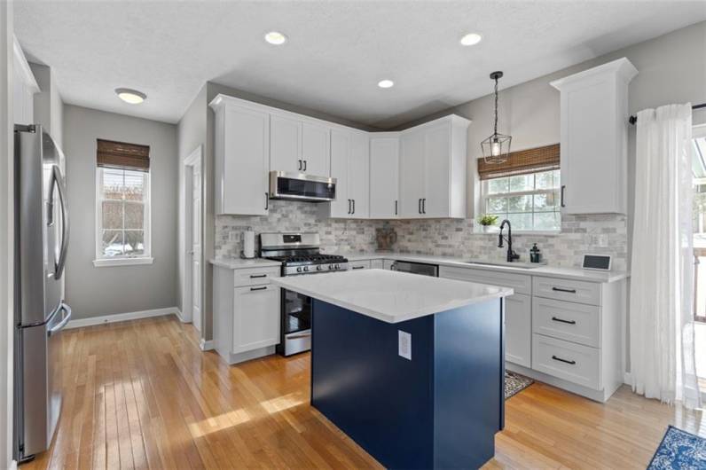 Beautifully updated kitchen featuring sleek quartz countertops, a spacious island, dual-tone cabinetry, and stainless-steel appliances – a perfect blend of style and function.