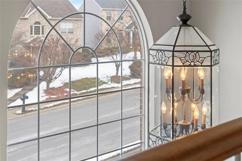 Stunning two-story foyer with a graceful Palladian window, framing beautiful views of the outdoors and welcoming natural light.