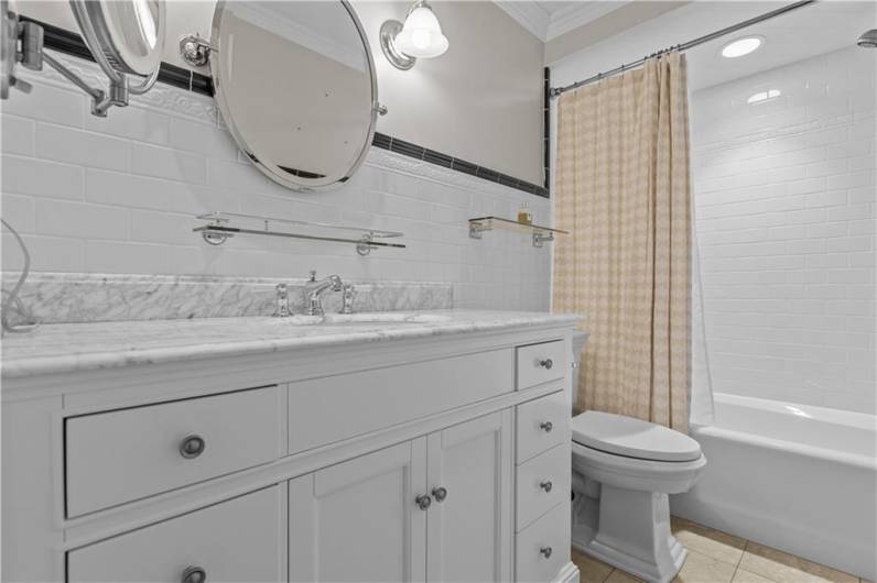 The Hall Bath Features a Marble Topped Vanity and ub/Shower Combo with Custom Tile Surround