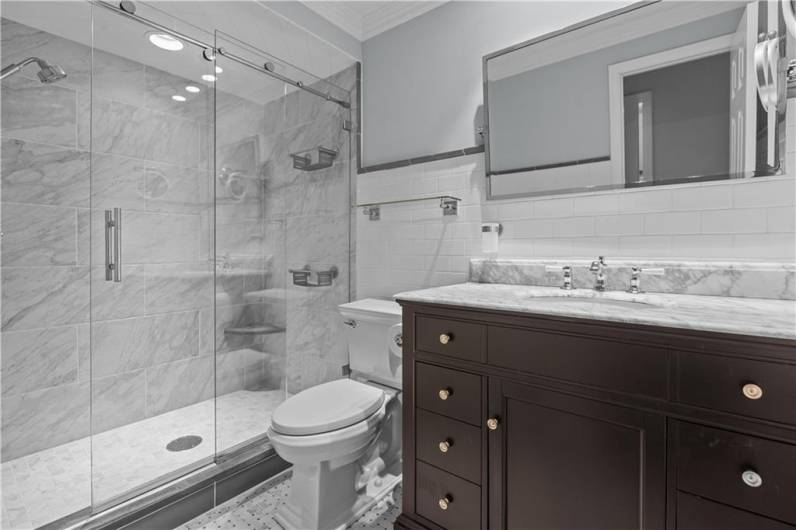 The Renovated Primary Bath Features a Marble Topped Vanity and Custom Tile Walk-In Shower