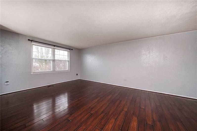 The expansive living room with low-maintenance flooring is bathed in abundant natural light, creating a bright and welcoming atmosphere.