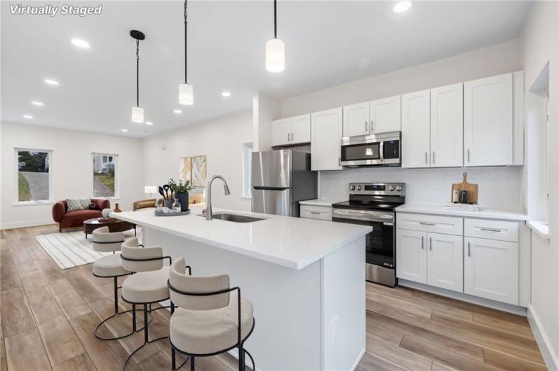 Beautiful new kitchen with quartz counters, stainless appliances and a kitchen island for cooking or gathering