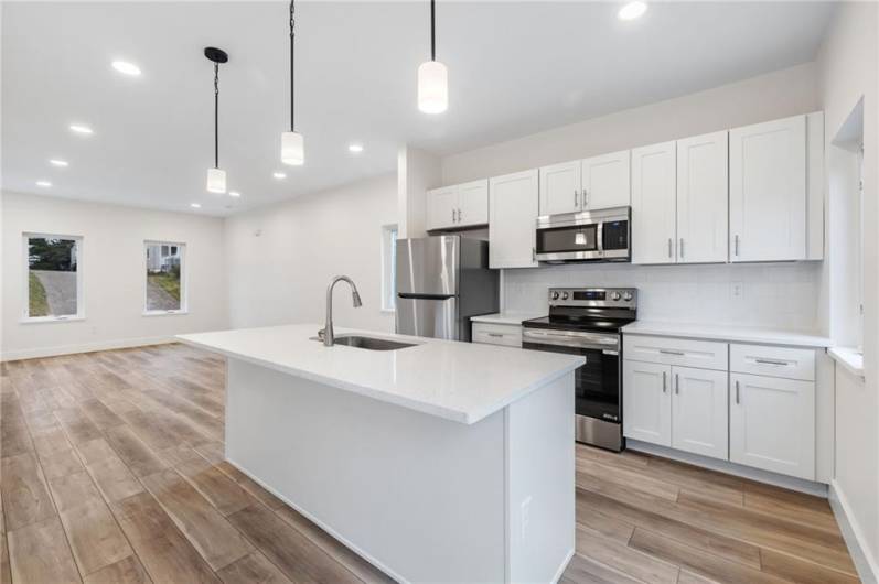 Beautiful new kitchen with quartz counters, stainless appliances and a kitchen island for cooking or gathering