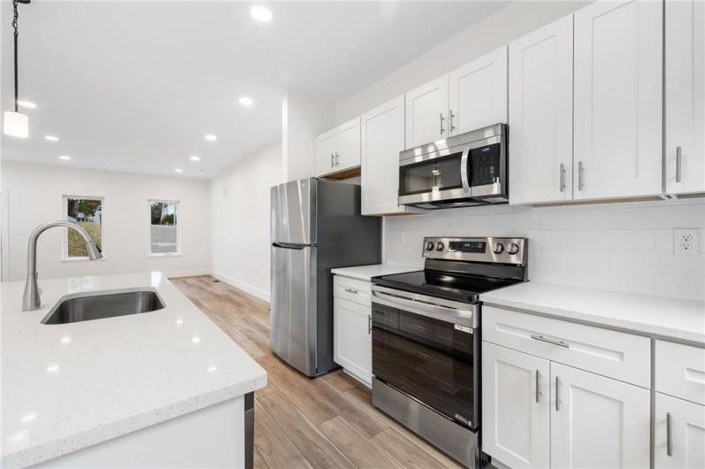 Beautiful new kitchen with quartz counters, stainless appliances and a kitchen island for cooking or gathering