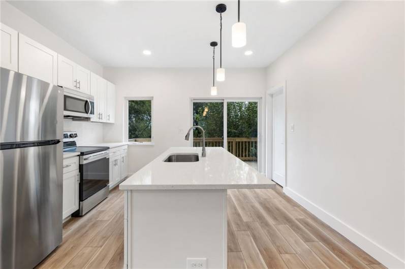 Beautiful new kitchen with quartz counters, stainless appliances and a kitchen island for cooking or gathering