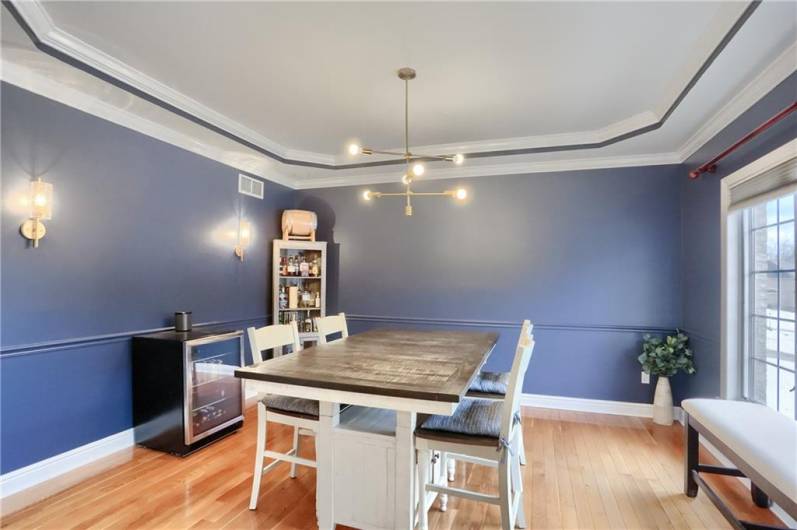 Beautiful sconces glisten on the stylish paint tone of the spacious dining room with a tray ceiling.