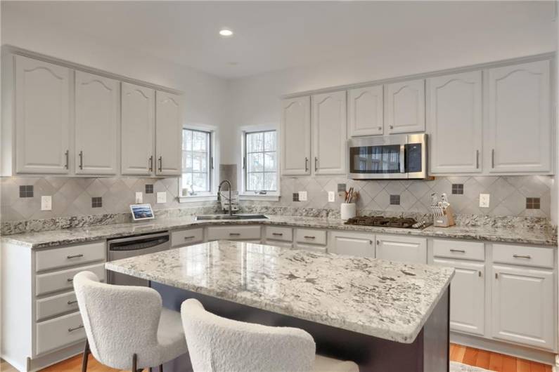 Luminous lighting above the cabinets and below showcases the complementary, custom backsplash and neutral paint tone.