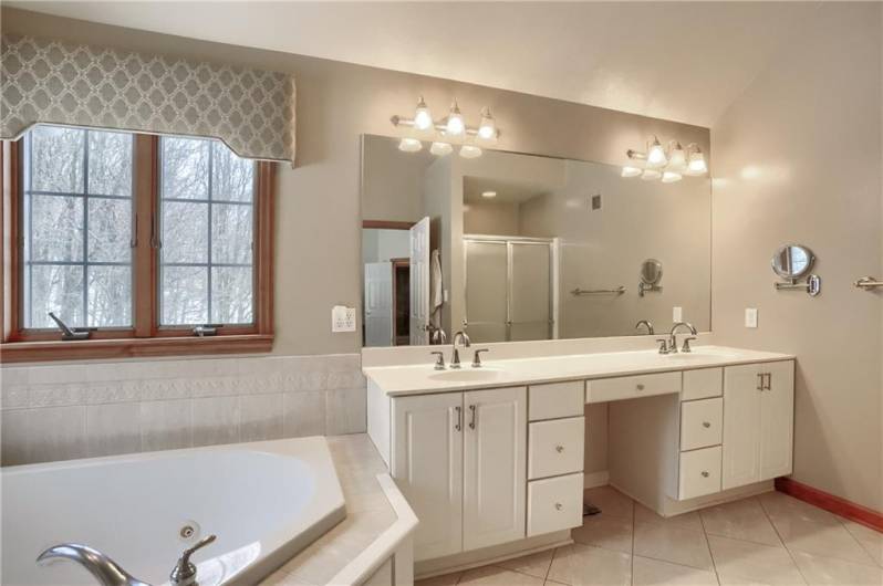 Start and end days in the spa like bathroom with a corner jet tub, a large dual sink vanity, shower and a water closet.