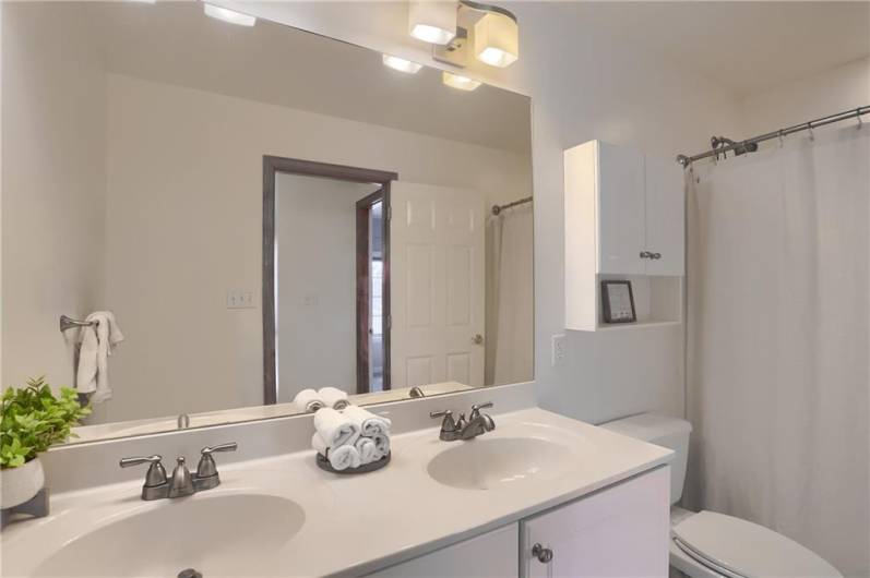 A shared hall bathroom features a dual sink vanity and a tub/shower combo.