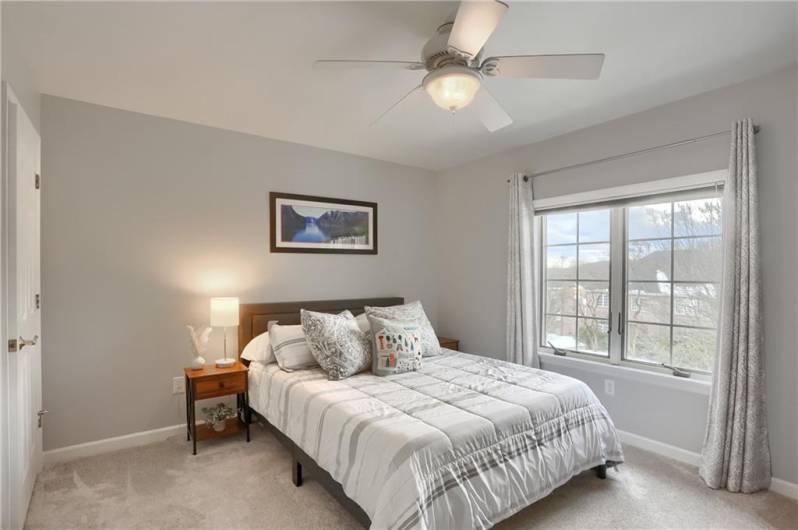 Another spacious and well lit guest bedroom with a walk in closet and ceiling fan.