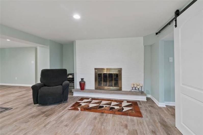 Another view of the spacious newly remodeled lower level finished game room area with a log burning fireplace, easy access to the 4th bedroom/office/den, and additional kitchen, too. New flooring and paint!