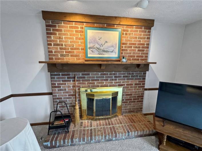 Family room fireplace with mantel and spotlights.