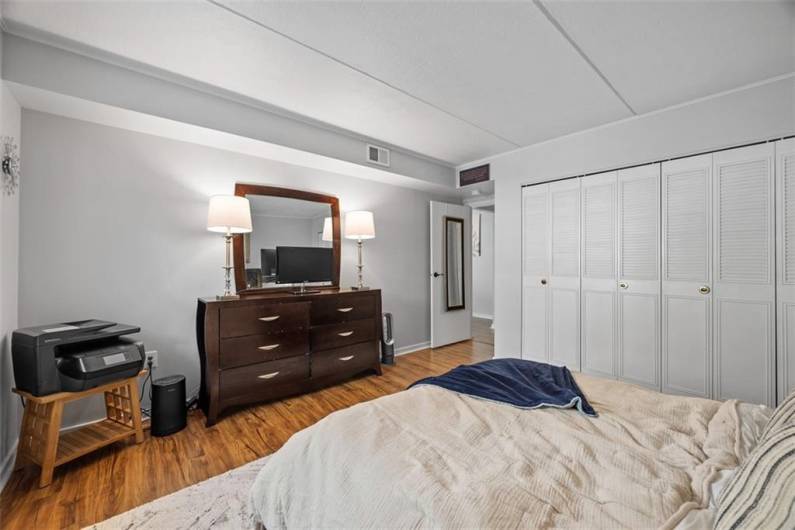 Primary bedroom with wall of closet with built-in closet organizer.  LVP flooring