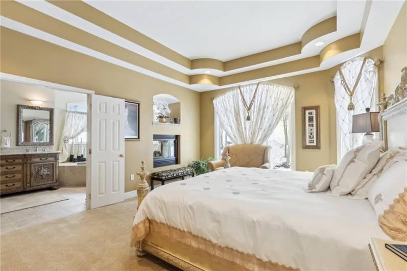 First floor guest suite with triple trey ceiling, walls of windows and two side fireplace.