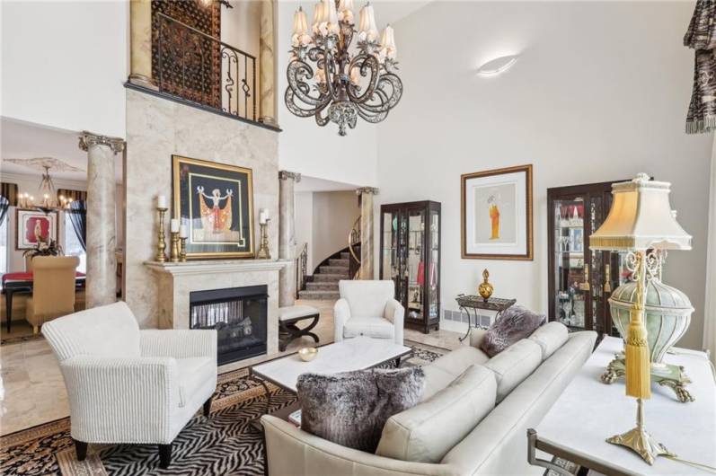 Two story family room with a spectacular fireplace accented by a Travertine wall and appealing wood mantel.