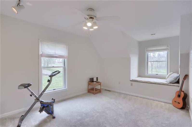 This guest bedroom features a charming window seat for enjoying the view.