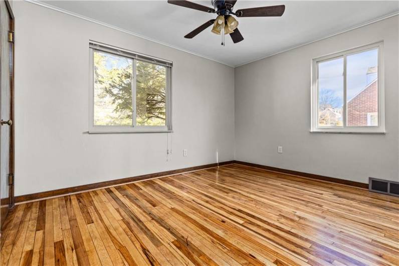 Bedroom with light/fan combination and refinished hardwood flooring.