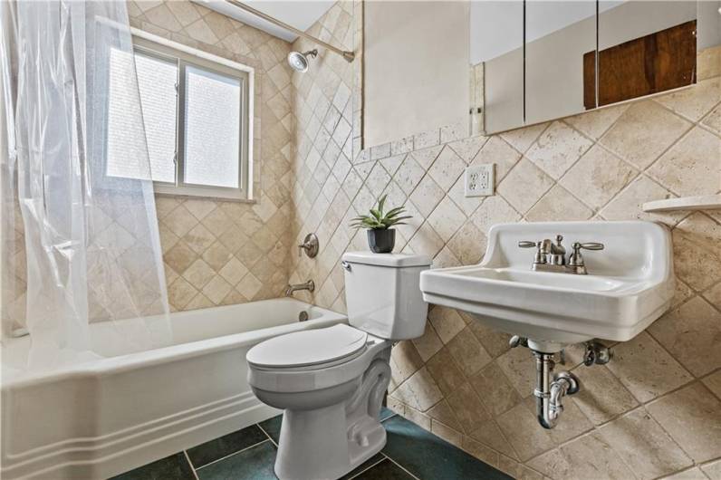 Renovated bathroom with travertine tile and beautiful flooring tile.